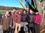 Seven retreat participants in winter clothing standing in front of a tree.
