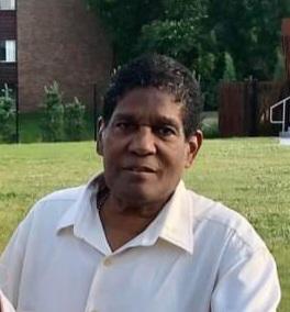 Headshot of Edgar Hicks in white button up shirt in front of green grass