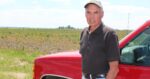 portrait of Jack Erisman standing in front of a red pickup truck wearing a ballcap