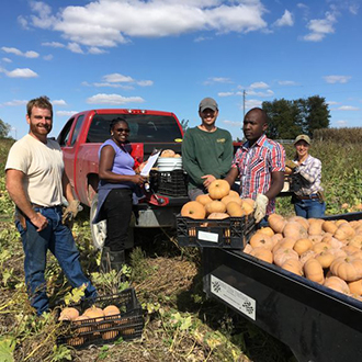 group of people stand next to truck with squash