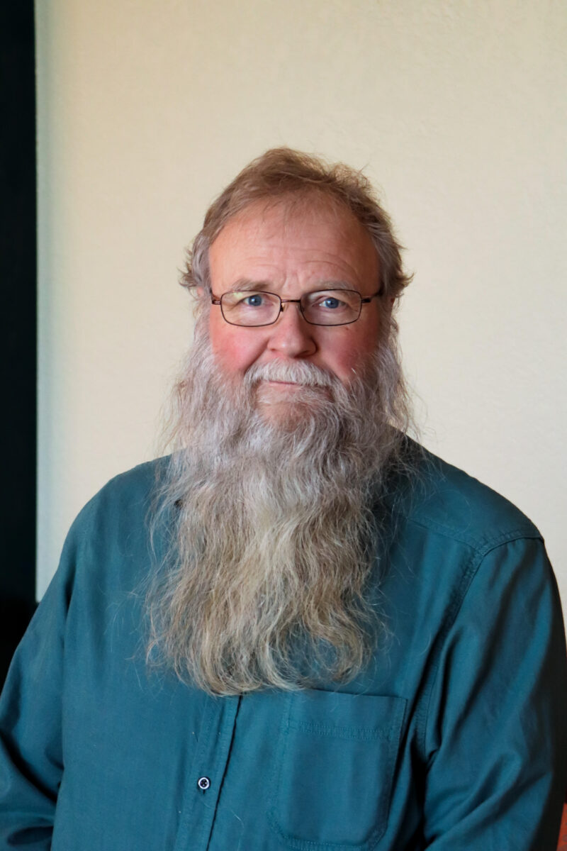 man with long beard, glasses, and blue shirt
